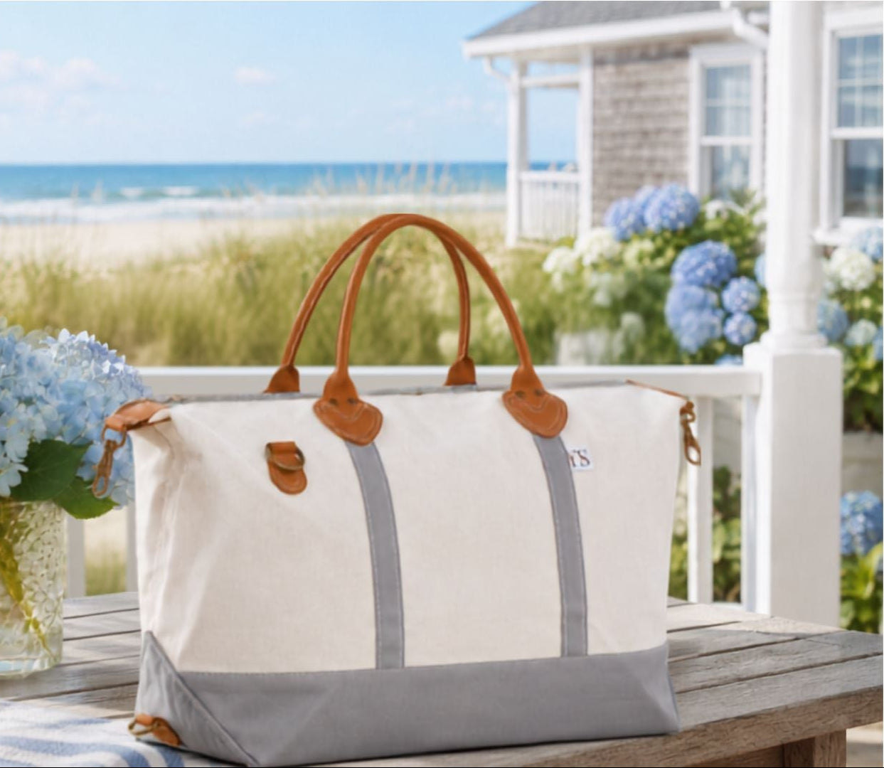White and gray tote bag with brown handles on a porch with beach view